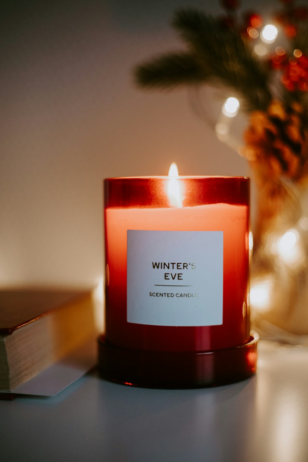 a red candle sitting on top of a table next to a book