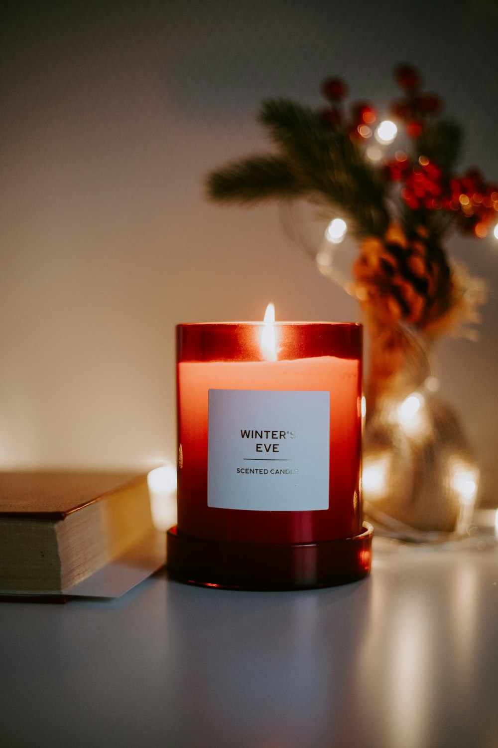 a red candle sitting on top of a table next to a book