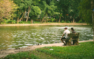 a man sitting on a bench next to a lake