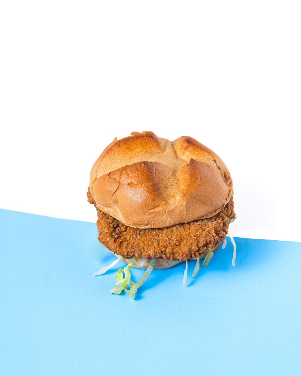 a chicken sandwich sitting on top of a blue surface