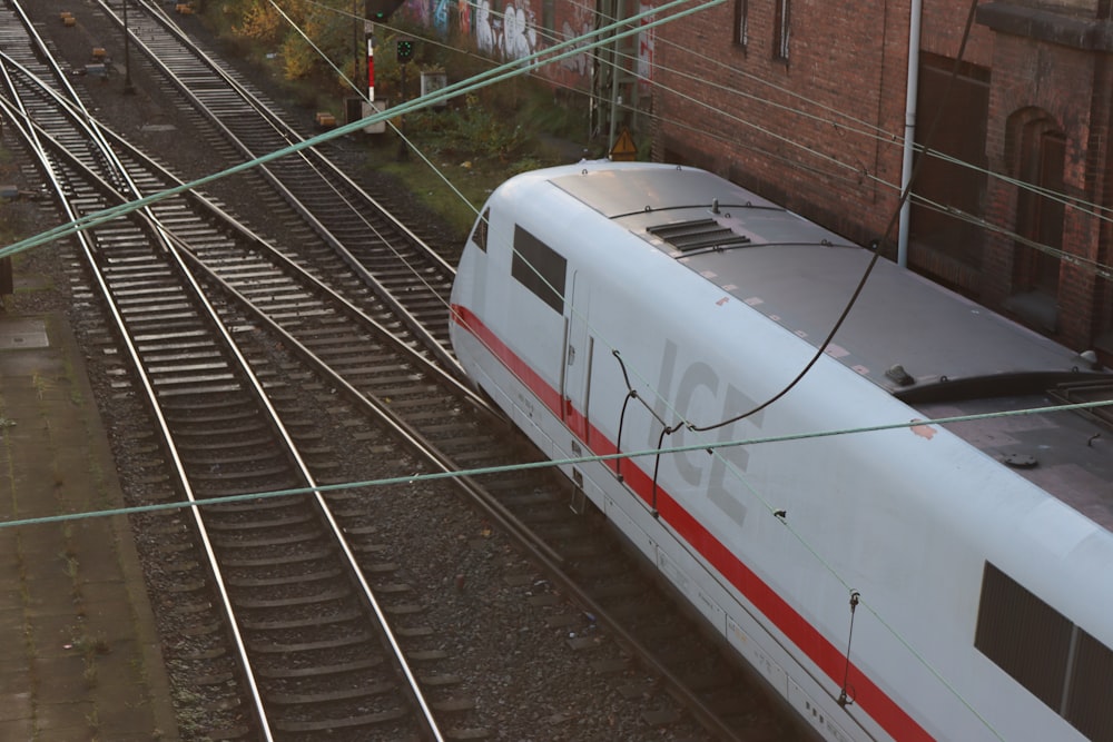 a white train traveling down train tracks next to a building