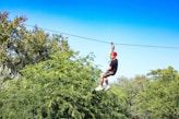 a man riding a zip line through a forest