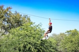 a man riding a zip line through a forest