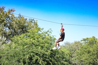 a man riding a zip line through a forest