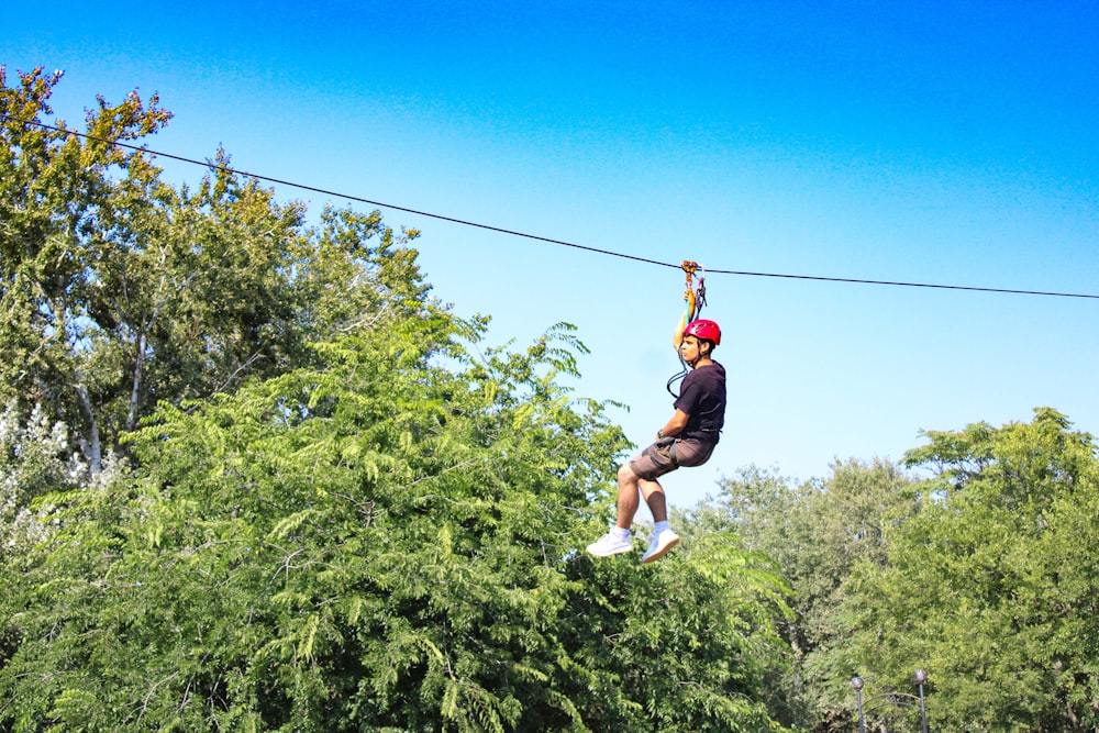 a man riding a zip line through a forest