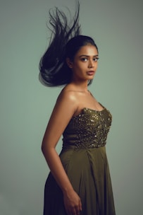 Elegant female model wearing a flowing emerald dress against a white backdrop.