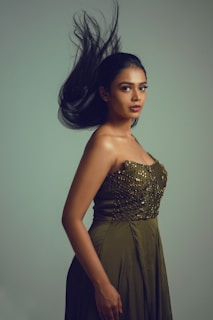 Elegant woman wearing a timeless olive green dress standing in a softly lit room with minimalist decor