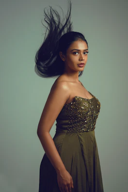 Elegant flowing dress in soft olive hues displayed against a rustic Istanbul workshop backdrop.