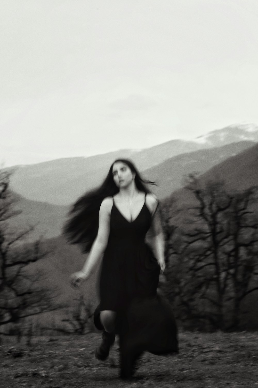 a woman in a black dress is walking in a field