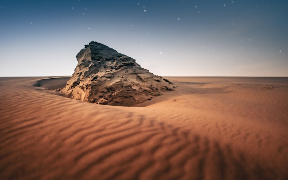 a large rock in the middle of a desert