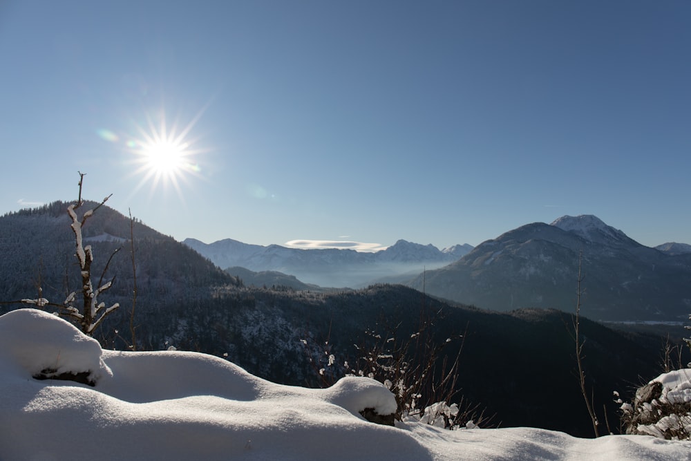 the sun shines brightly over a snowy mountain range