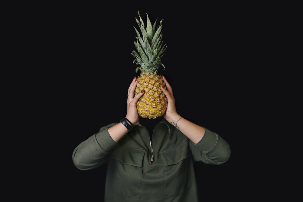 a person covering their face with a pineapple