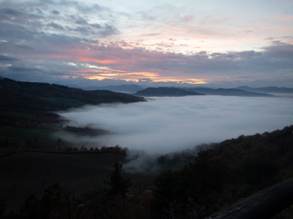 a view of a foggy valley with mountains in the distance