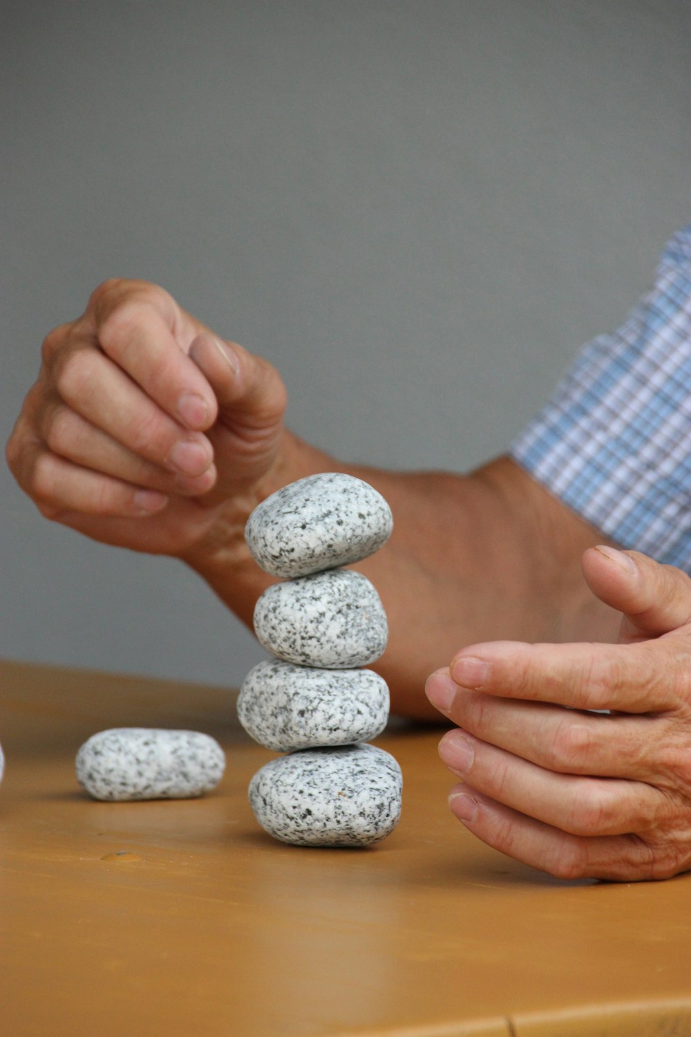 a man stacking rocks on top of a wooden table