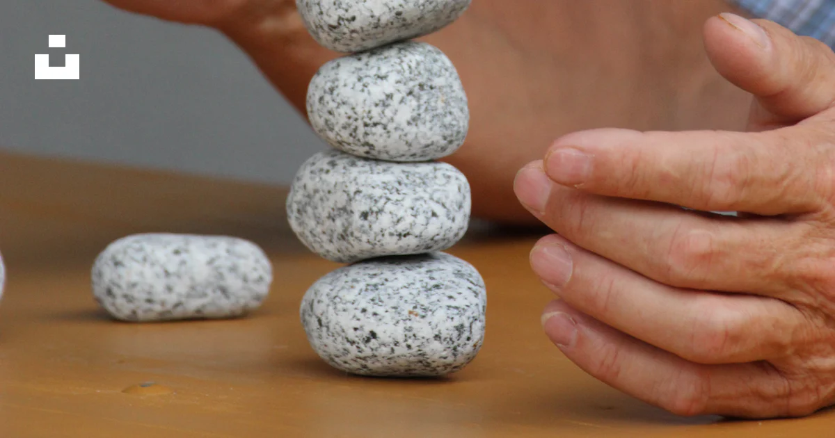 Man Stacking Rocks A man stacking rocks on top of a wooden table photo – Free Steinau an ...