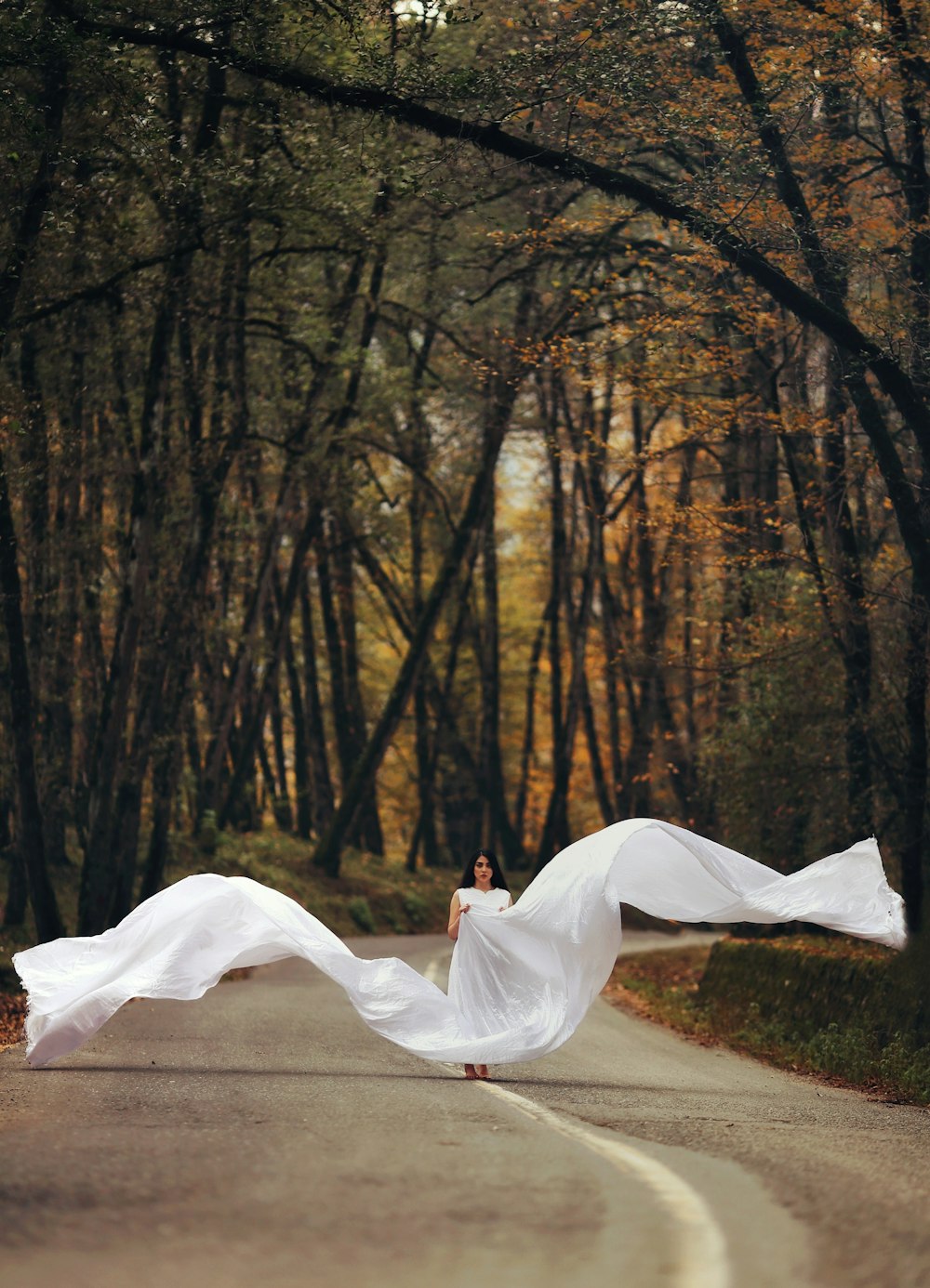 a woman in a white dress is running down the road