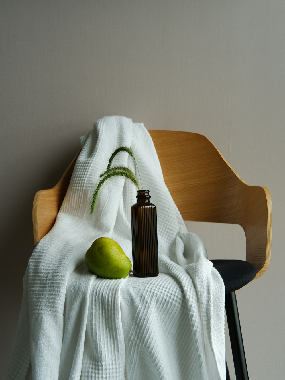 uma garrafa e uma pera em uma toalha em uma cadeira