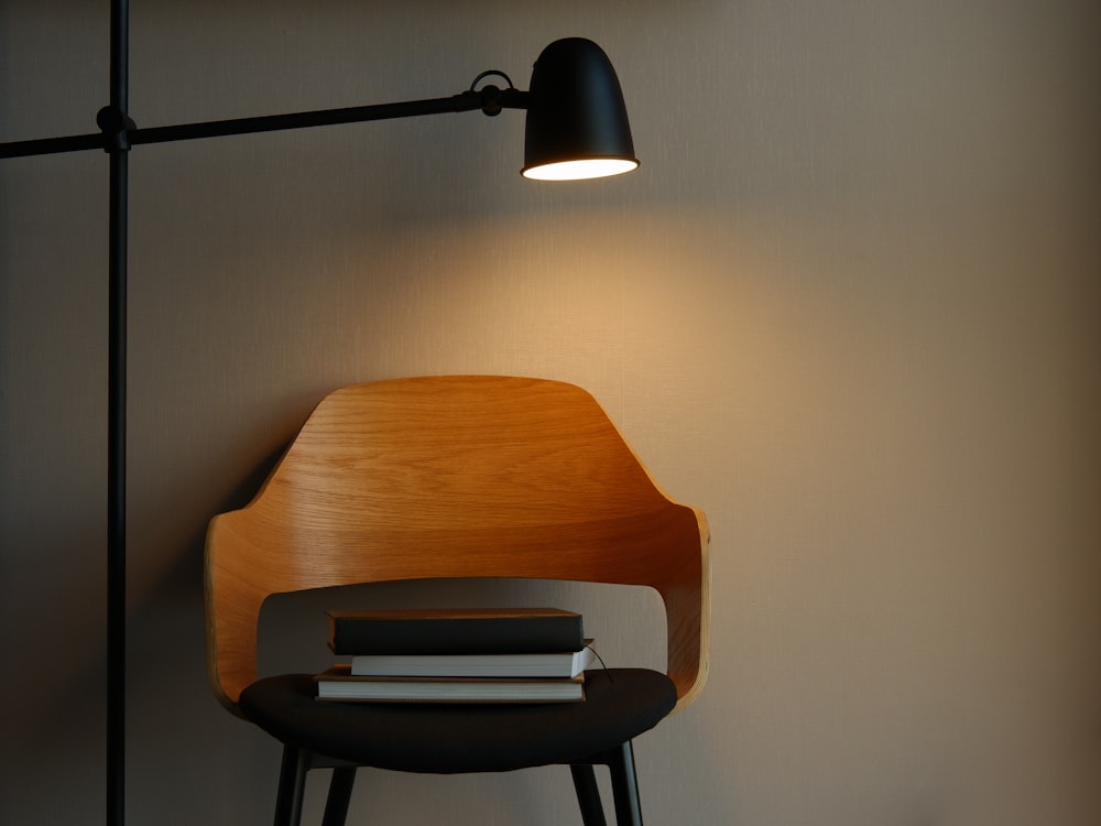 a wooden chair sitting next to a lamp on a wall