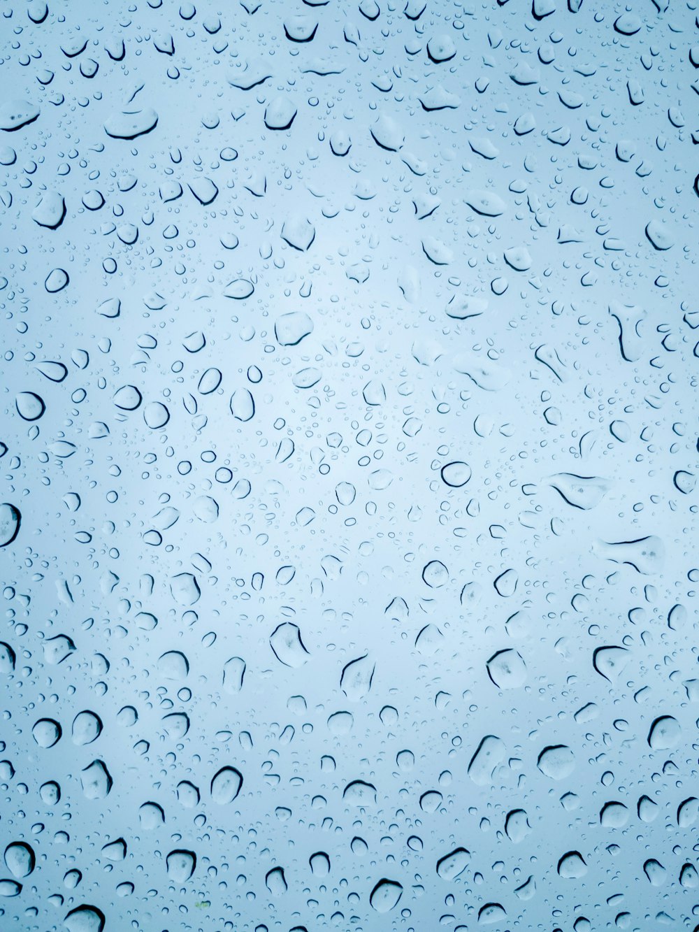 rain drops on a window with a blue sky in the background