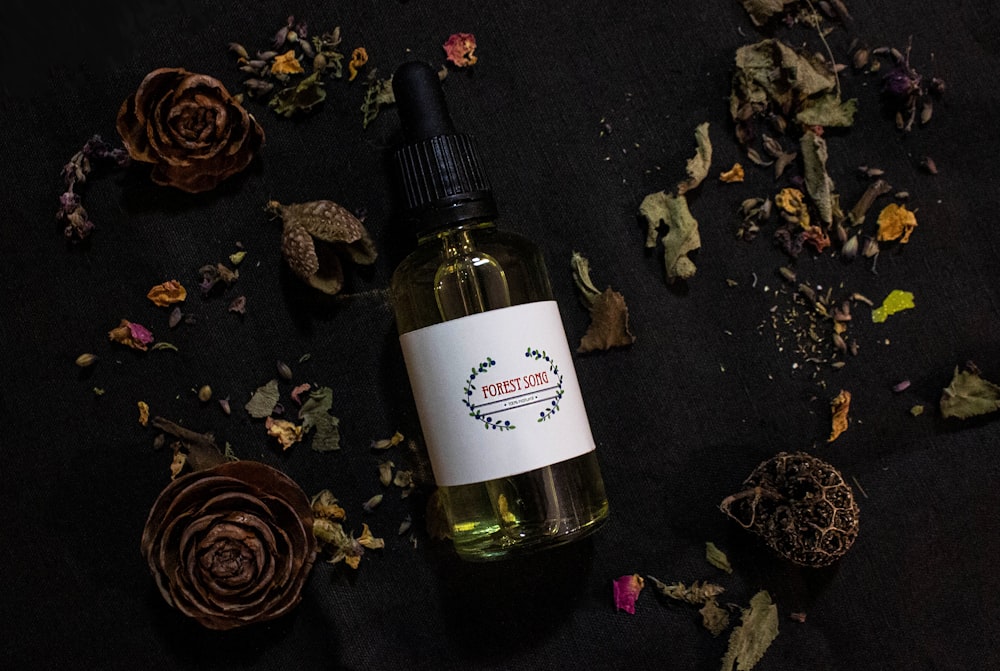 a bottle of essential oil surrounded by dried flowers