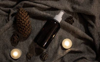 a bottle of lotion sitting on top of a bed next to candles