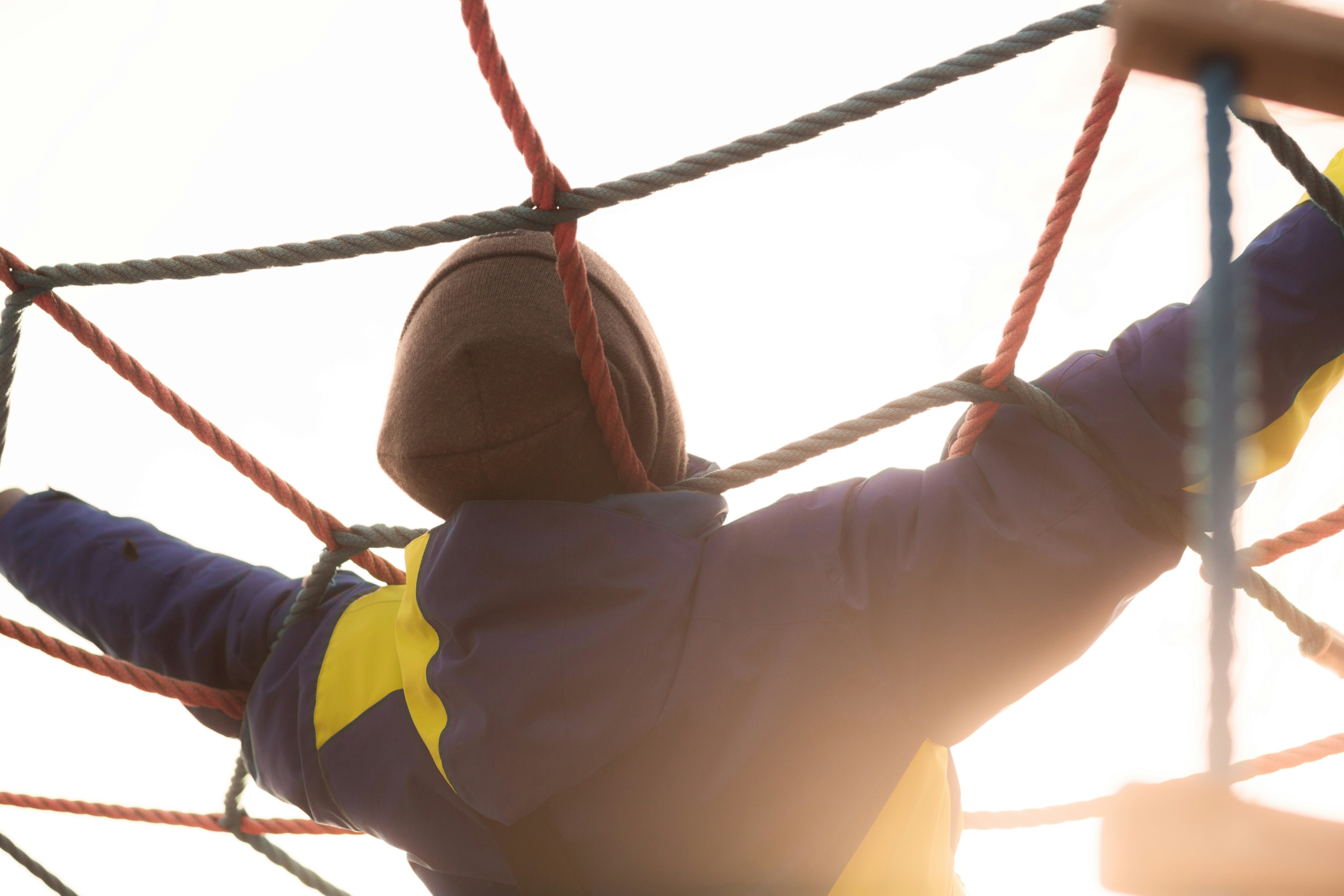 a person in a blue and yellow jacket on a rope course, 
