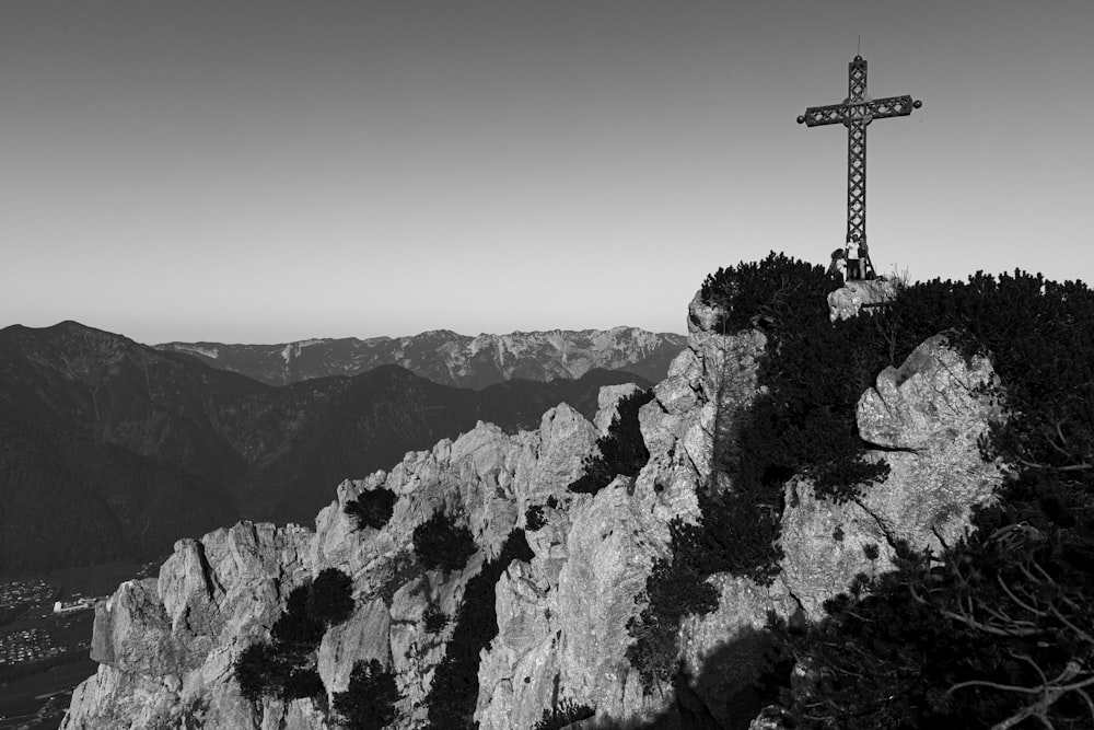 a black and white photo of a cross on top of a mountain