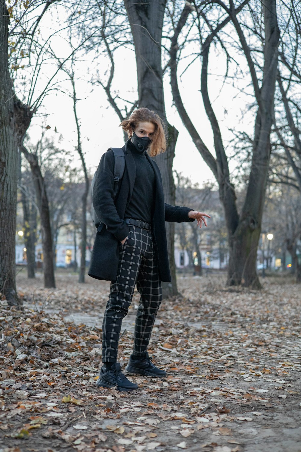 a woman standing in the leaves in a park