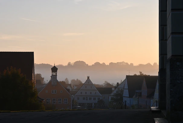 A serene sunrise over a secluded European village nestled by a calm river.