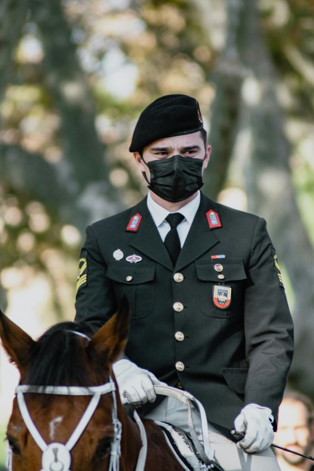 a man in uniform riding a horse wearing a face mask