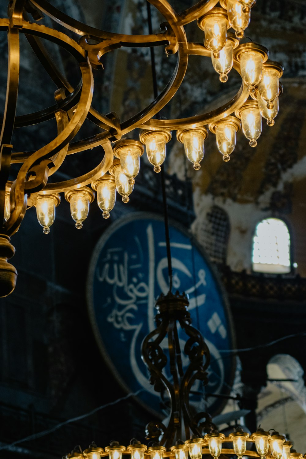 a chandelier hanging from a ceiling with a clock in the background