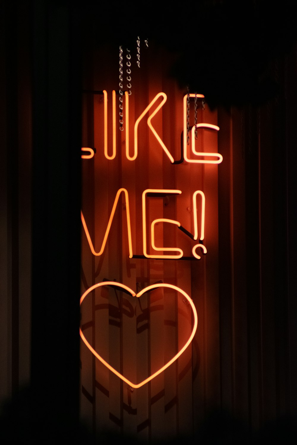 a neon sign that says like me with a heart