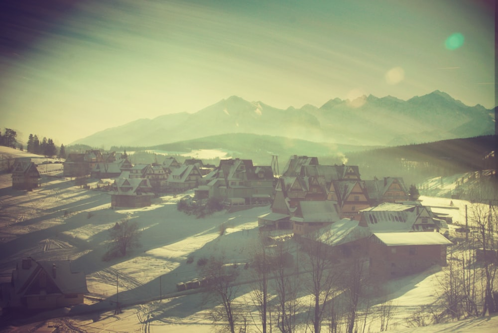 a snowy village with mountains in the background