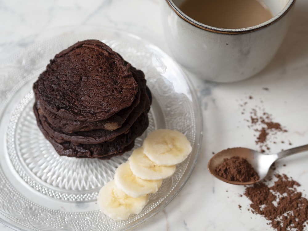 a stack of cookies on a plate next to a cup of coffee