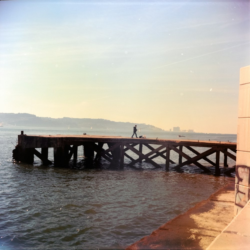 a person walking on a pier over a body of water