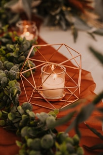a geometric brass candleholder sitting on top of a wooden table with red and green decor