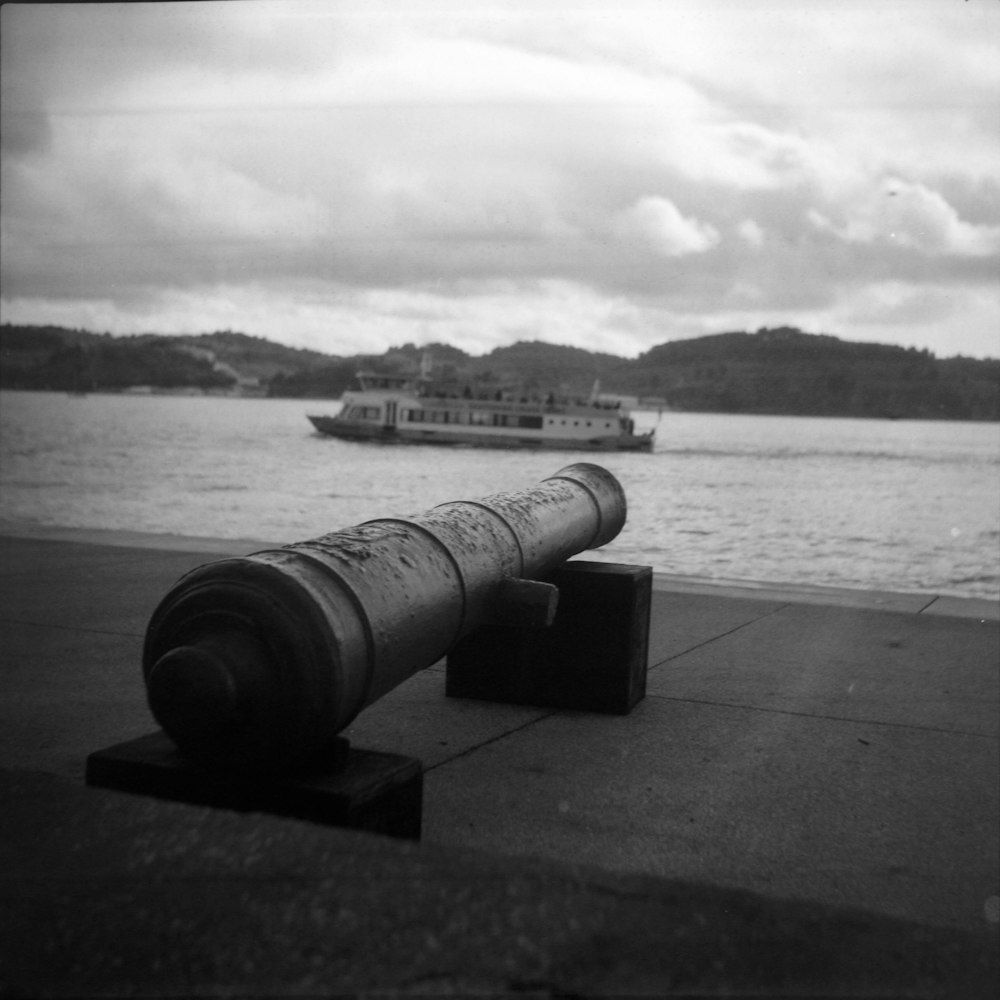 a cannon sitting on the ground next to a body of water