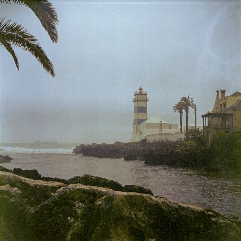 a light house sitting on top of a cliff next to a body of water