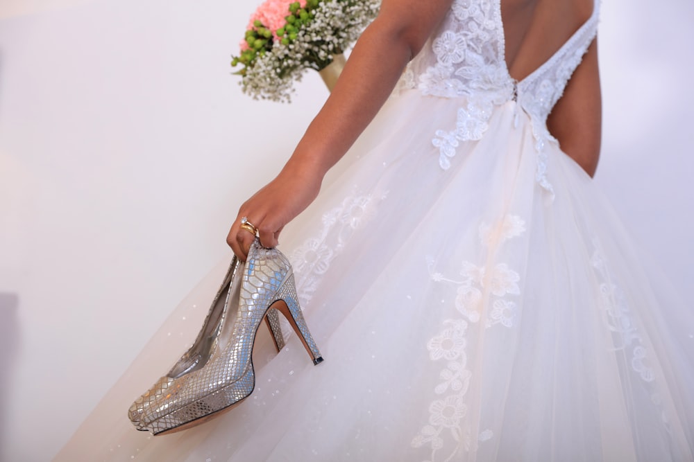 a woman in a wedding dress holding a high heeled shoe