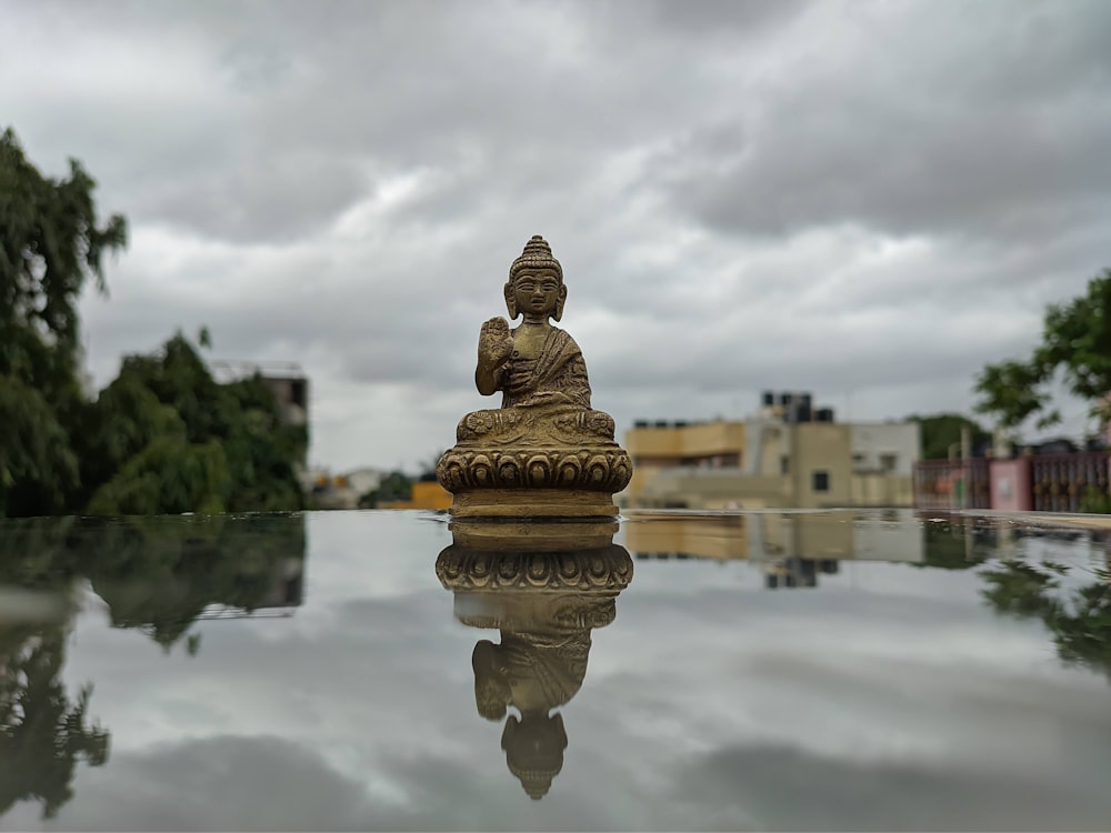 a buddha statue sitting on top of a reflective surface