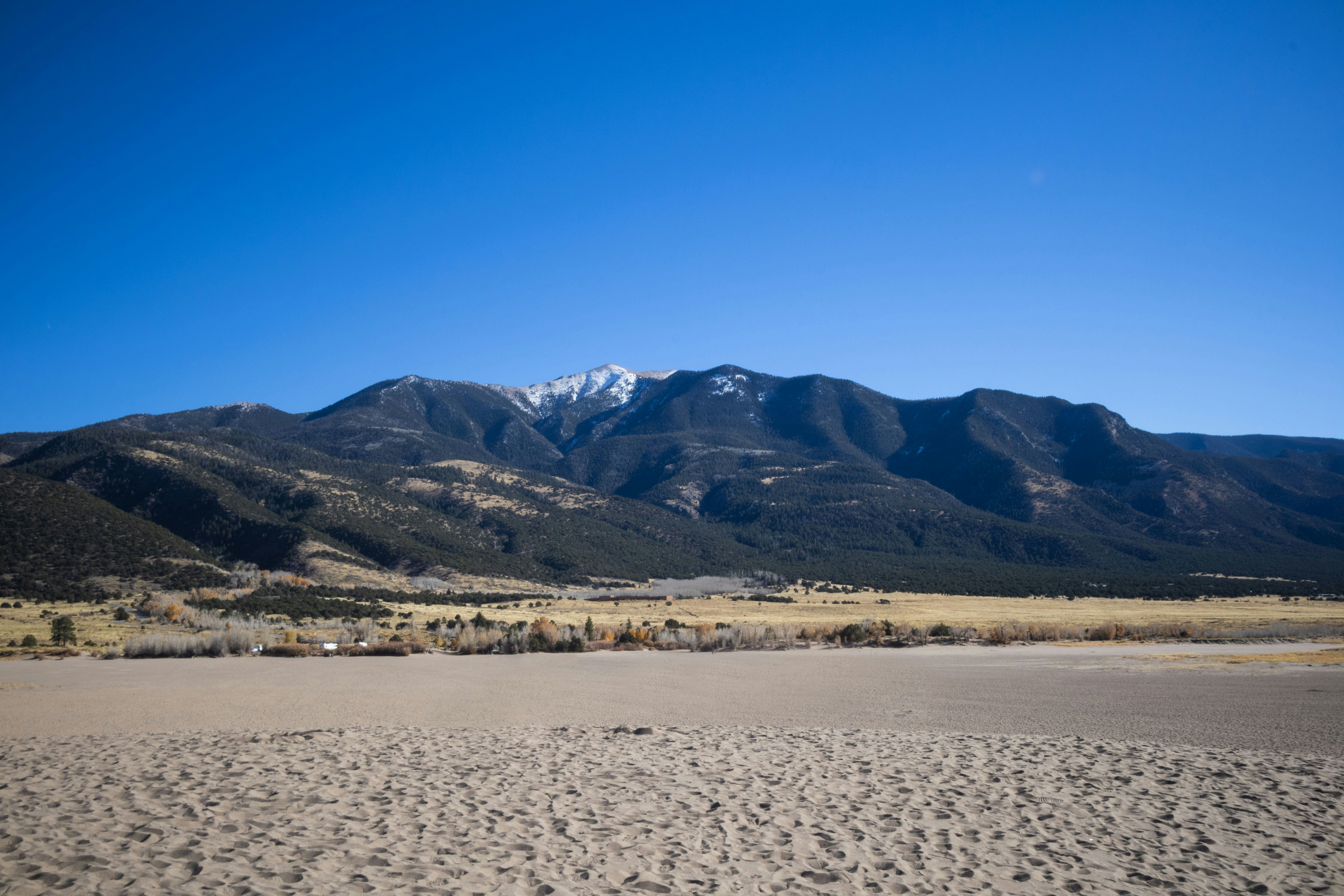 a sandy beach with mountains in the background, Mountainscape in the Distance