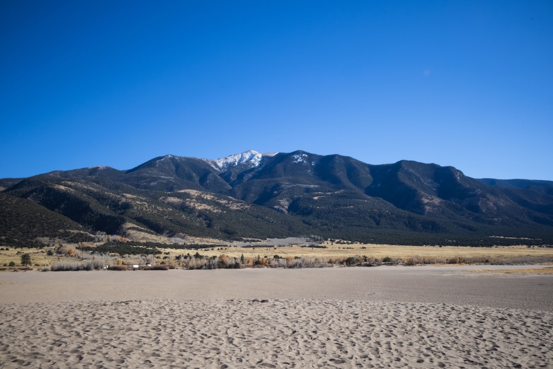 a sandy beach with mountains in the background, Mountainscape in the Distance