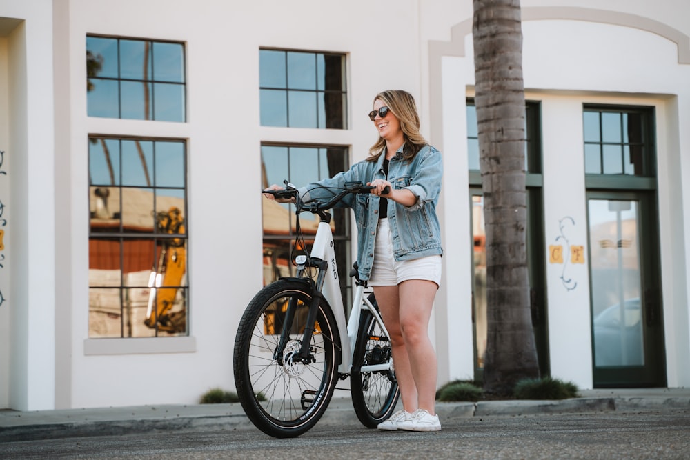 a woman standing next to a bike in front of a building