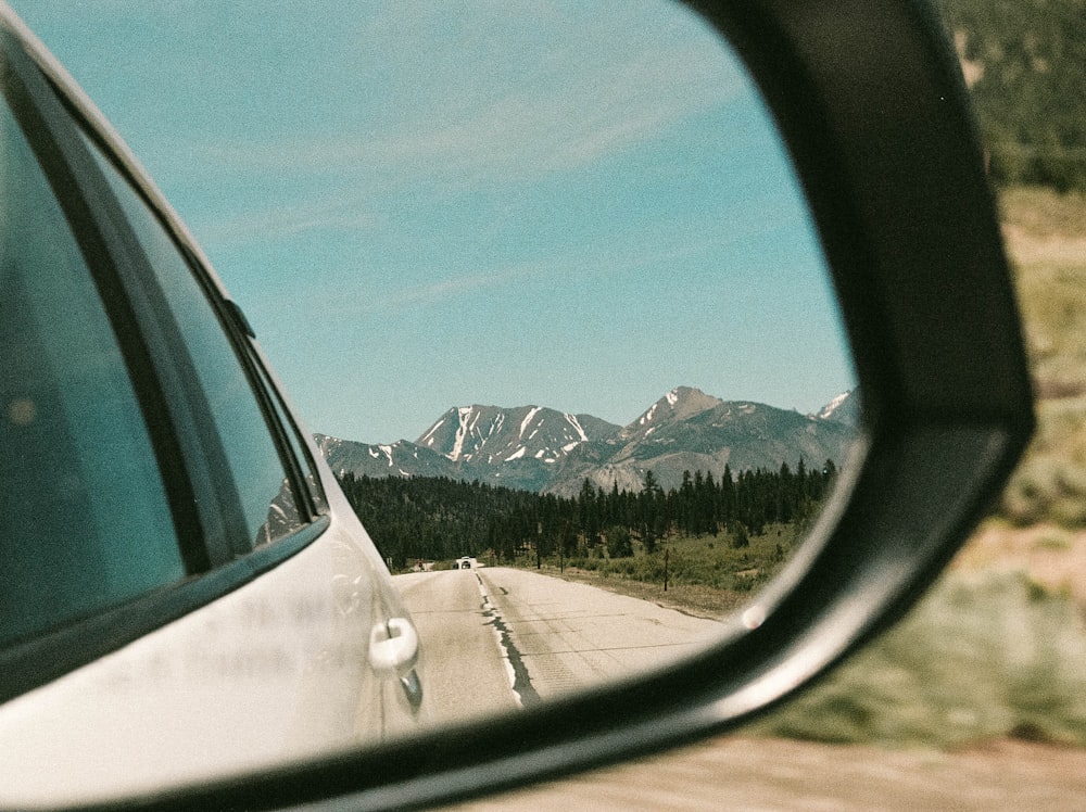 a car's side view mirror with mountains in the background