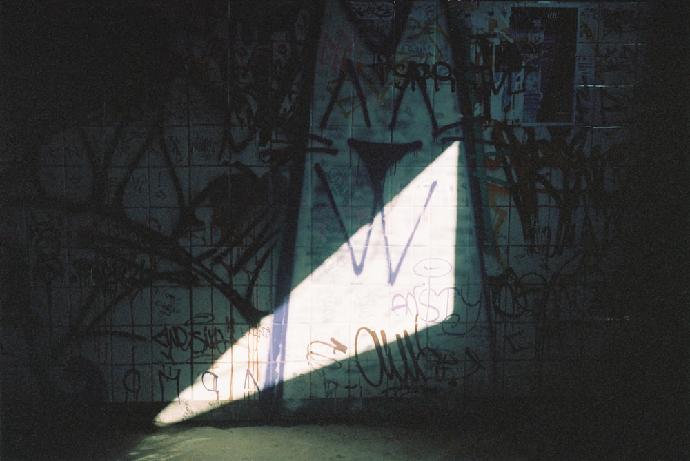 a shadow of a person standing in front of a wall covered in graffiti