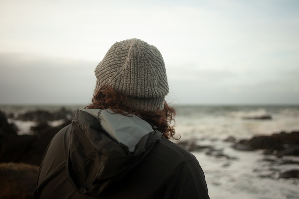 a person wearing a beanie looking out at the ocean