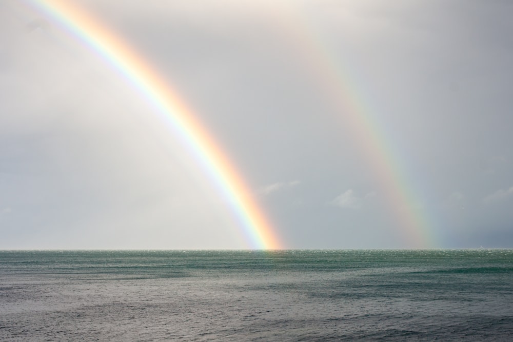 two rainbows in the sky over a body of water