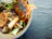 Close-up of a happy diner enjoying a colorful bowl of Mongolian Village Grill’s signature Asian fusion dish.