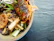Close-up of a happy diner enjoying a colorful bowl of Mongolian Village Grill’s signature Asian fusion dish.