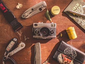a wooden table topped with a camera and other items